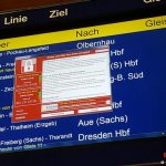 Компьютерное окно с требованием хакеров о выкупе поверх табло с расписанием поездов в Германии